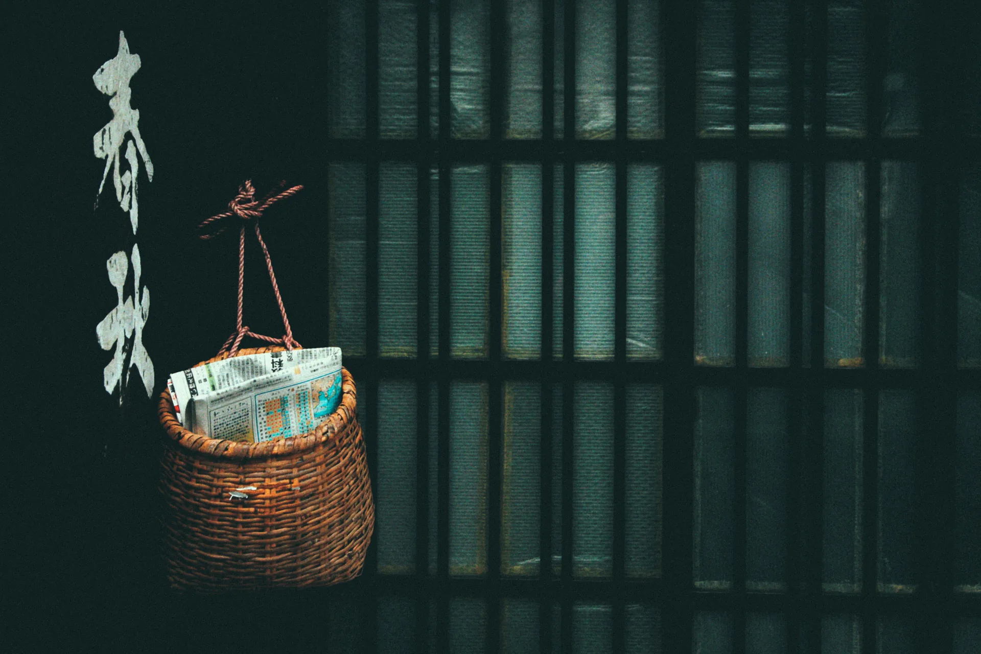 A wicker basket of newspapers hanging against a lattice window