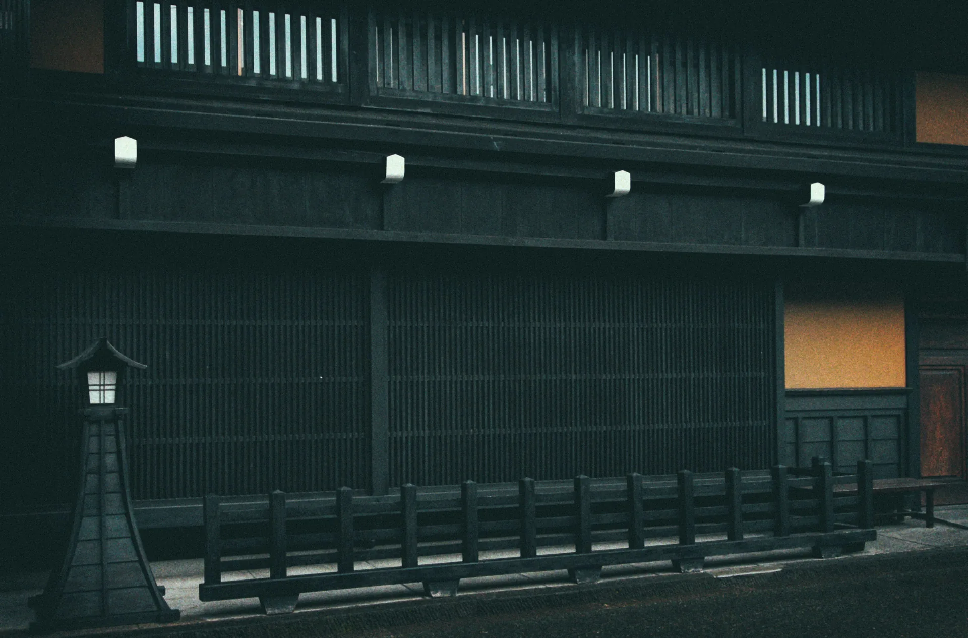 A stone lantern in front of a long wooden facade