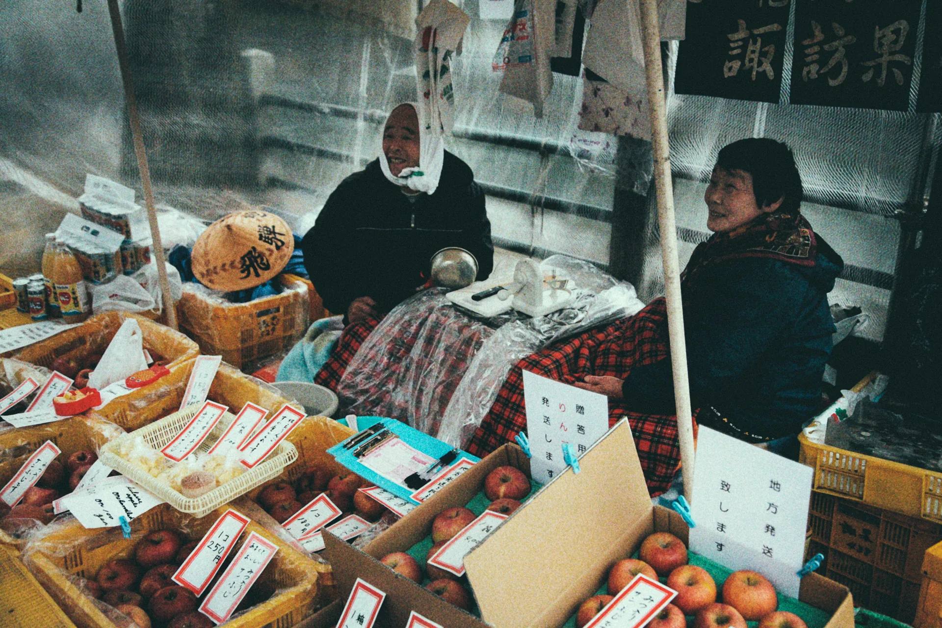 Two women selling apples and vegetables at the morning market