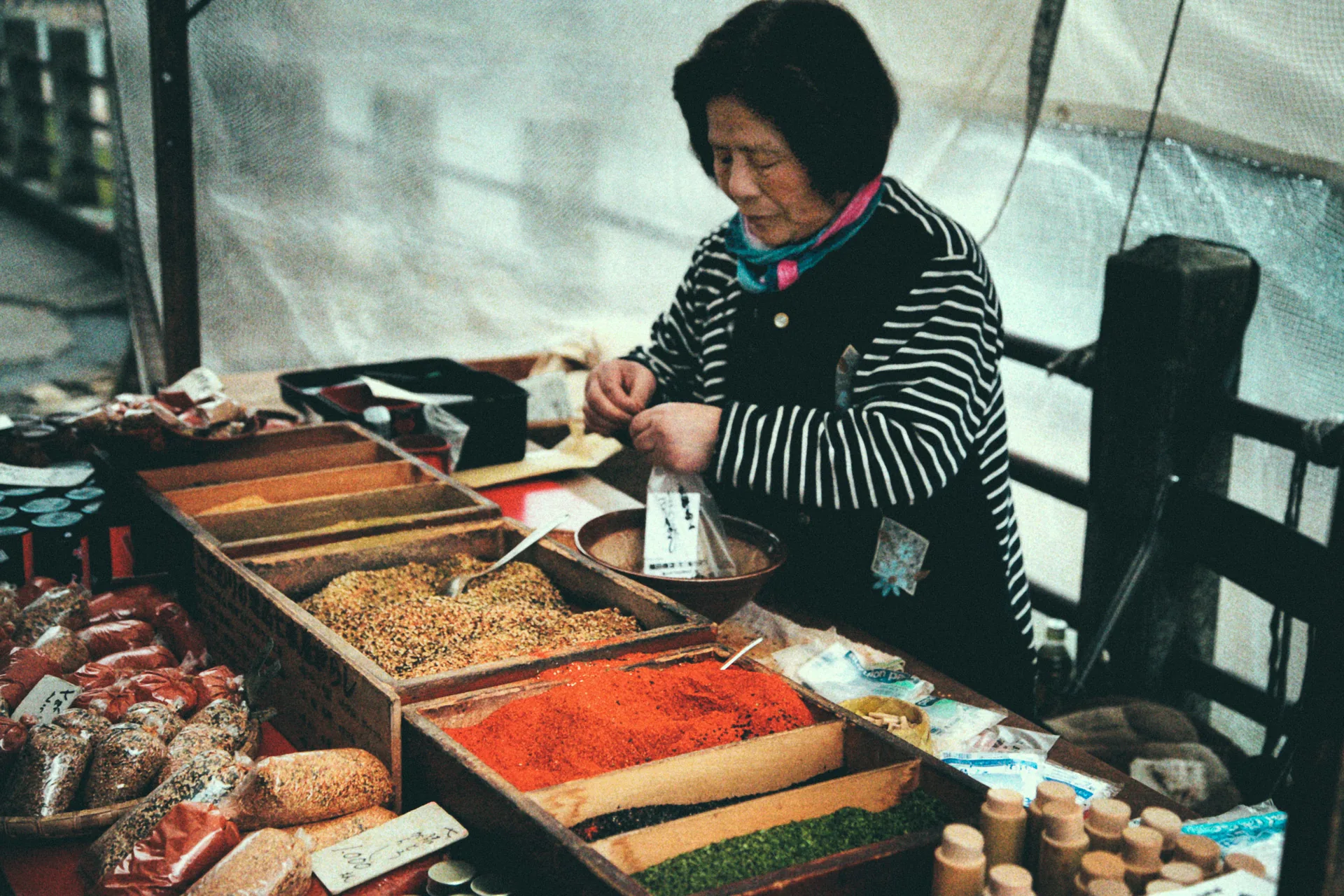 A woman measuring spices at a market stall