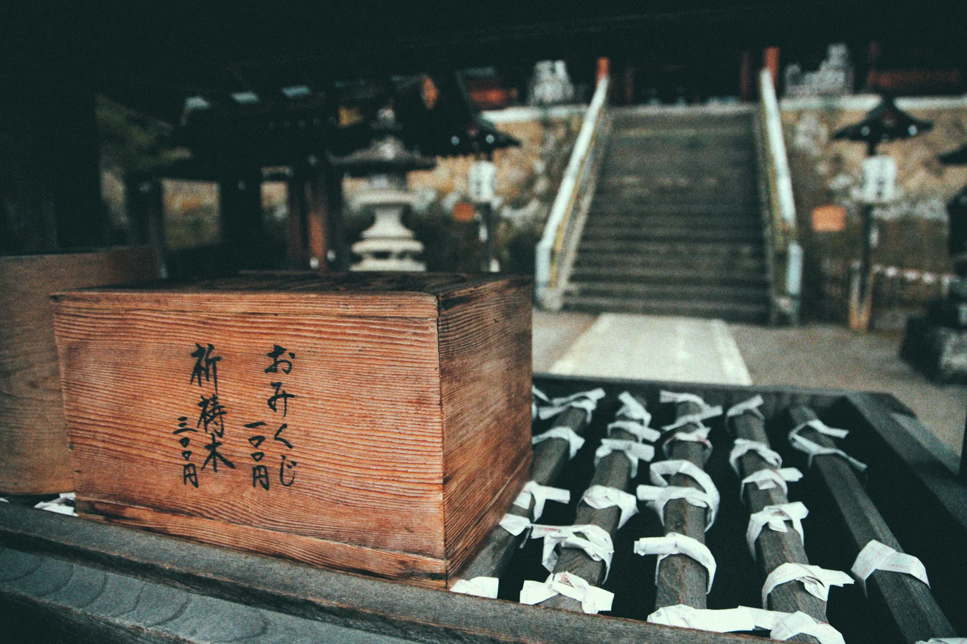 A wooden omikuji box at the foot of the shrine steps