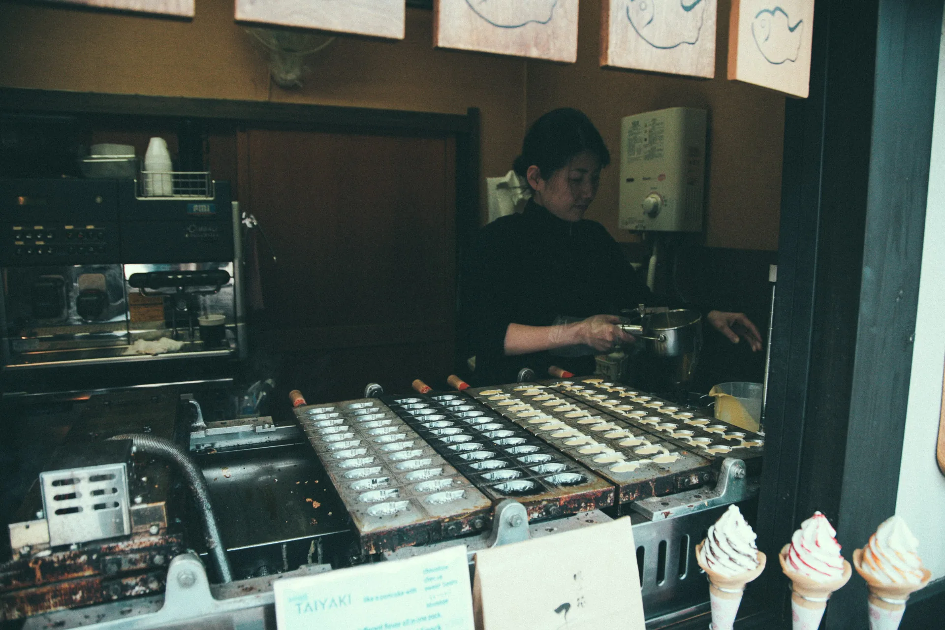 A woman making taiyaki at a street-side stall