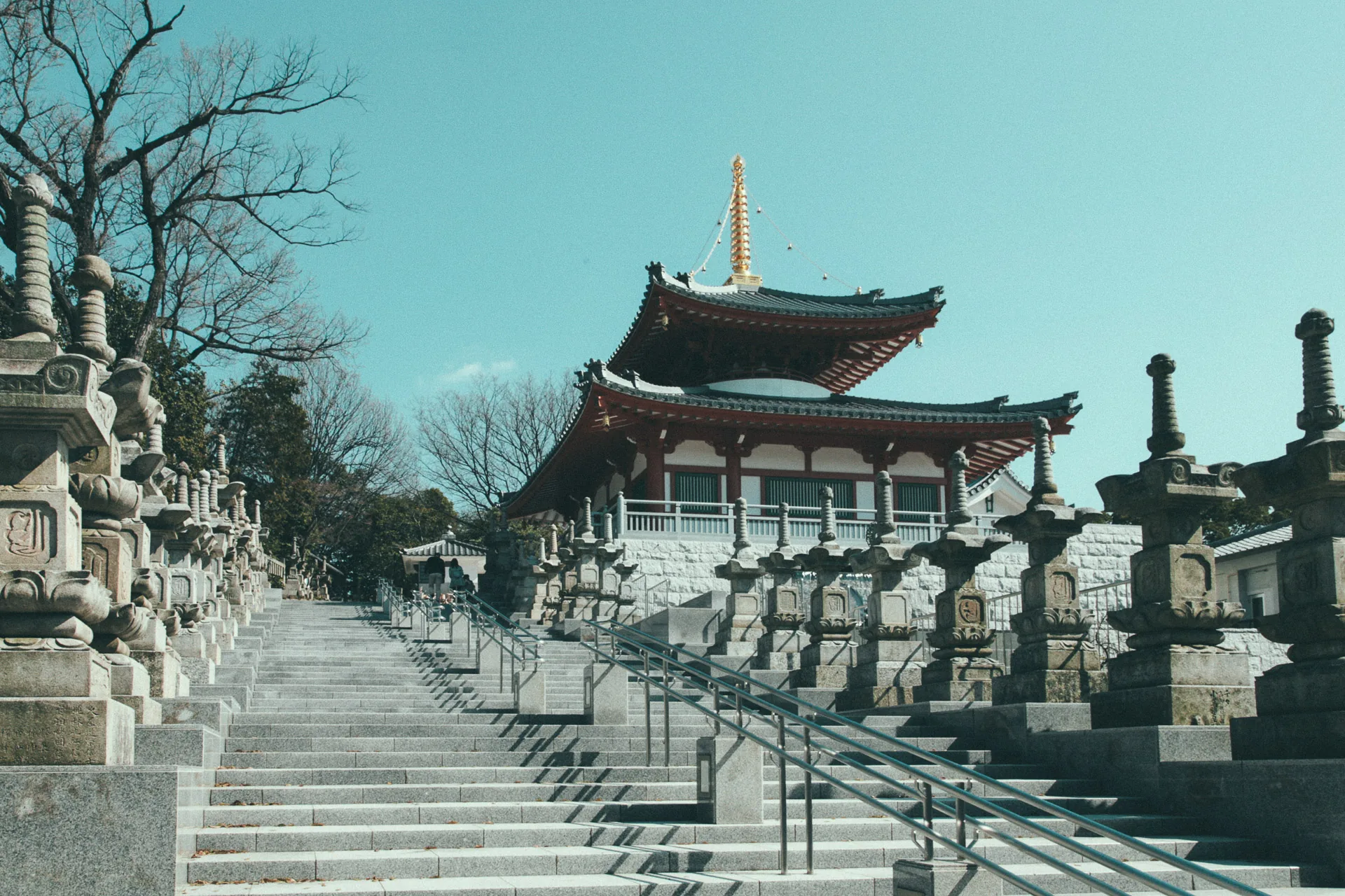 A pagoda above a stairway lined with stone lanterns