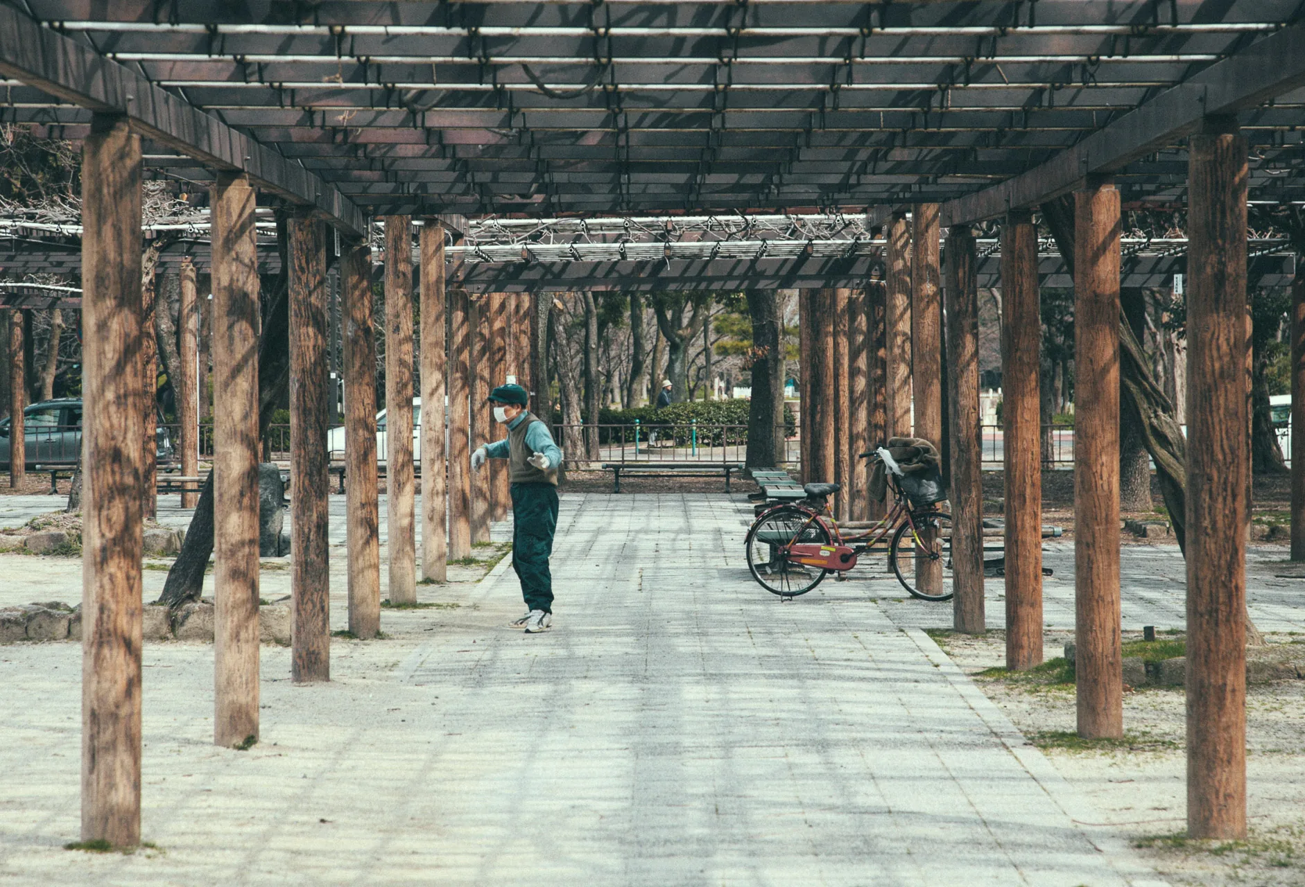 An elderly man exercising under a wooden pergola