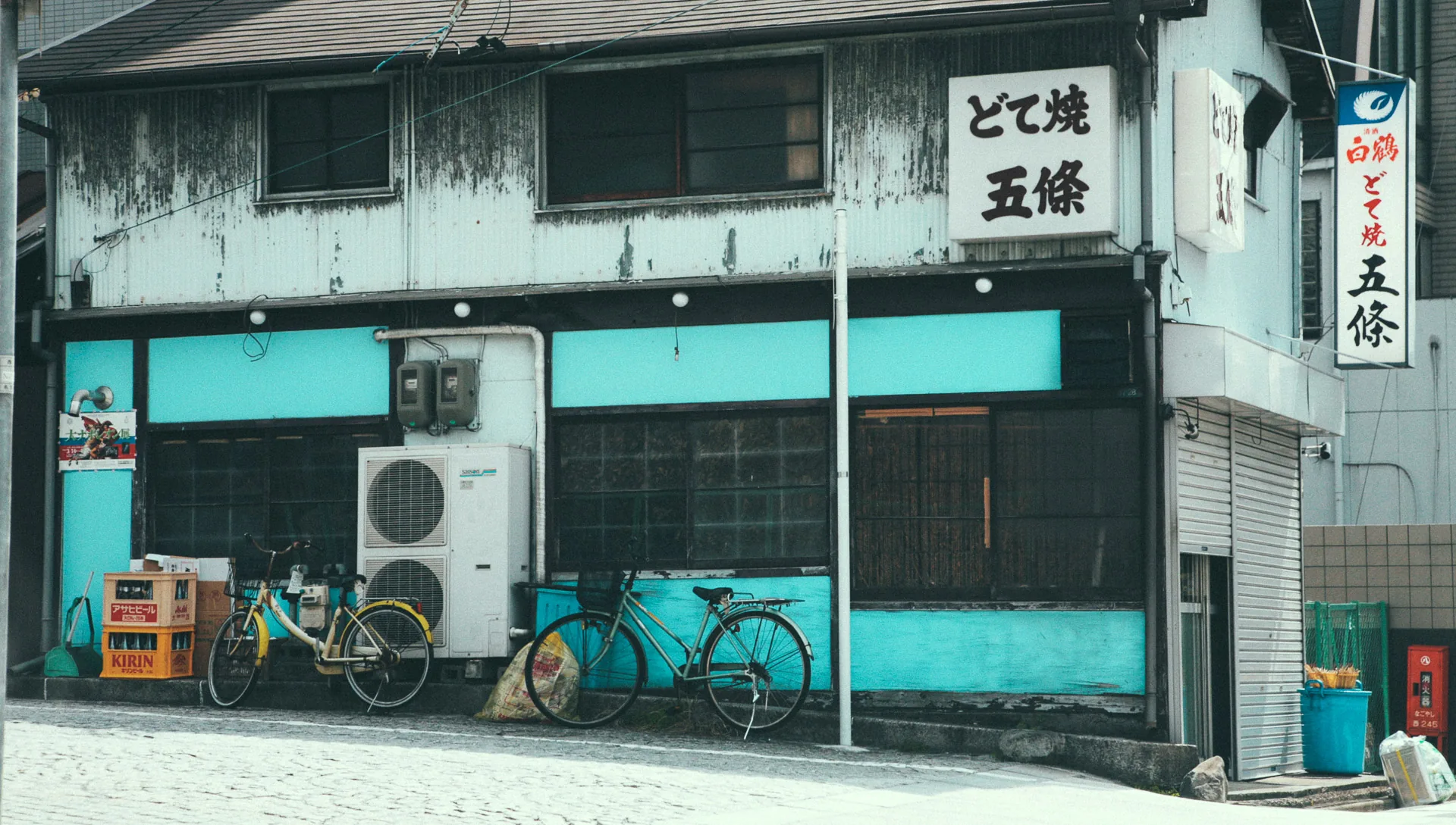 An old wooden shop with turquoise panels and bicycles