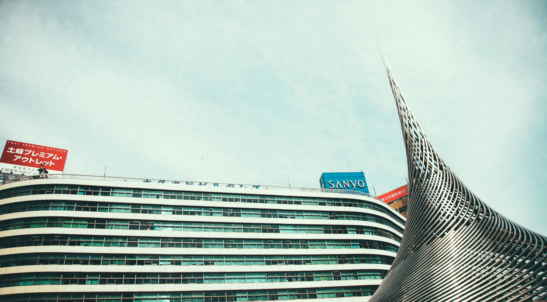 A department store and a curved steel sculpture by the station