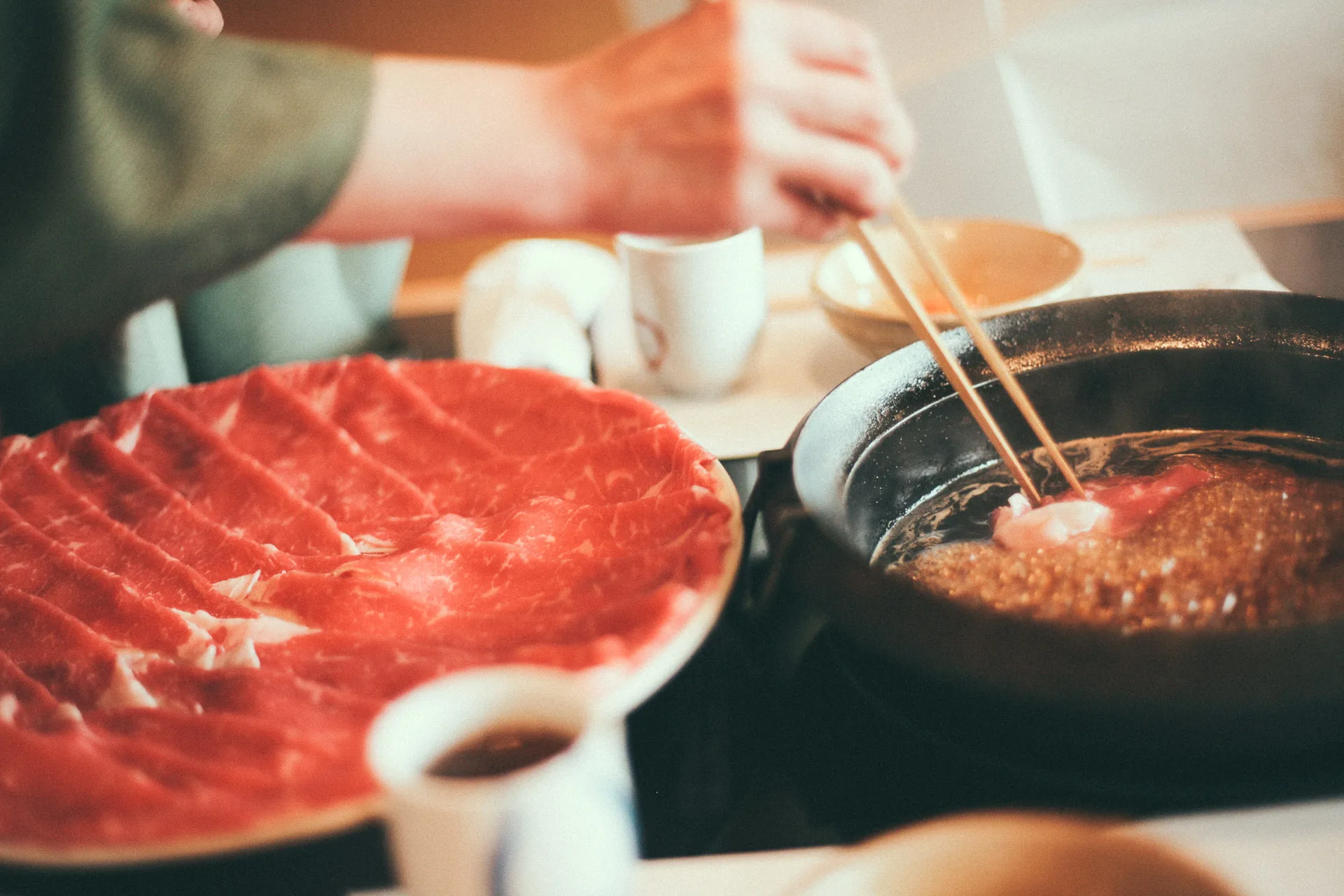 Thin slices of beef going into the sukiyaki pot