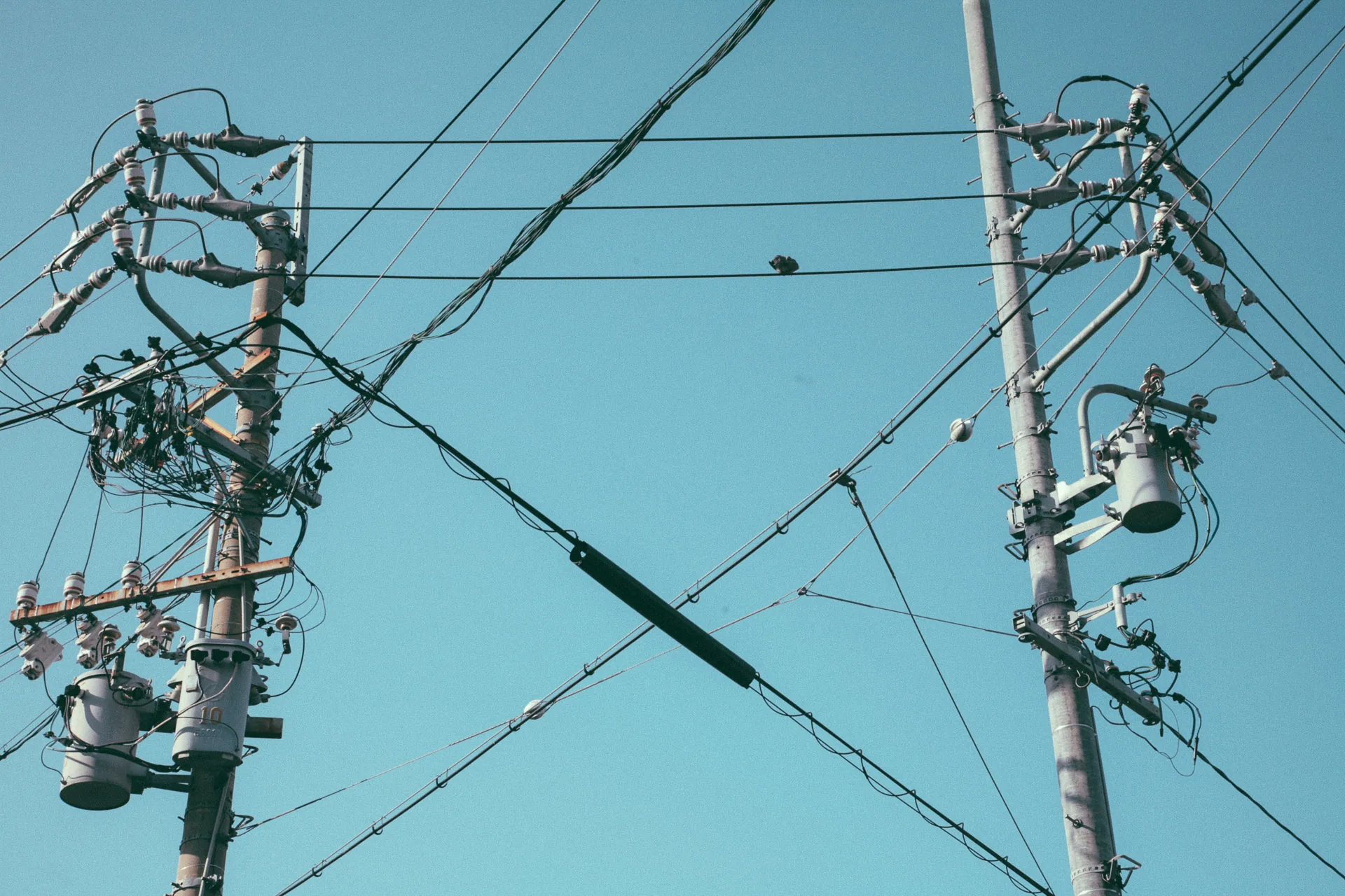 Utility poles and a tangle of wires against the blue sky