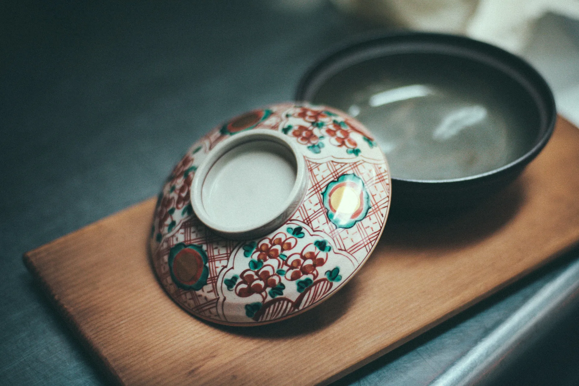 An antique porcelain bowl and lid on a wooden board