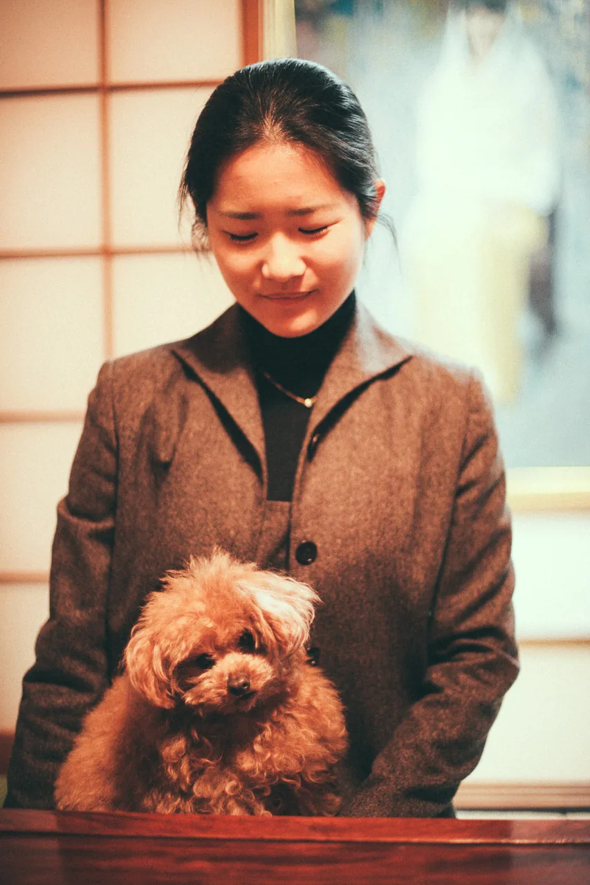 A young woman holding a toy poodle