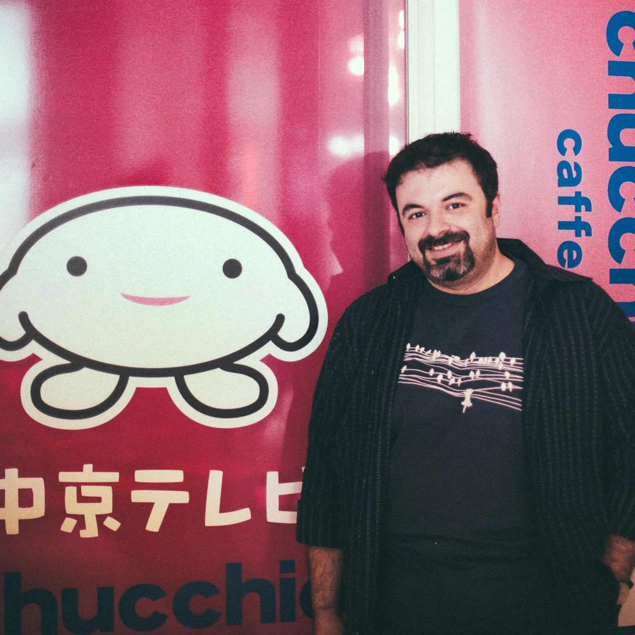 Standing next to a cartoon mascot poster