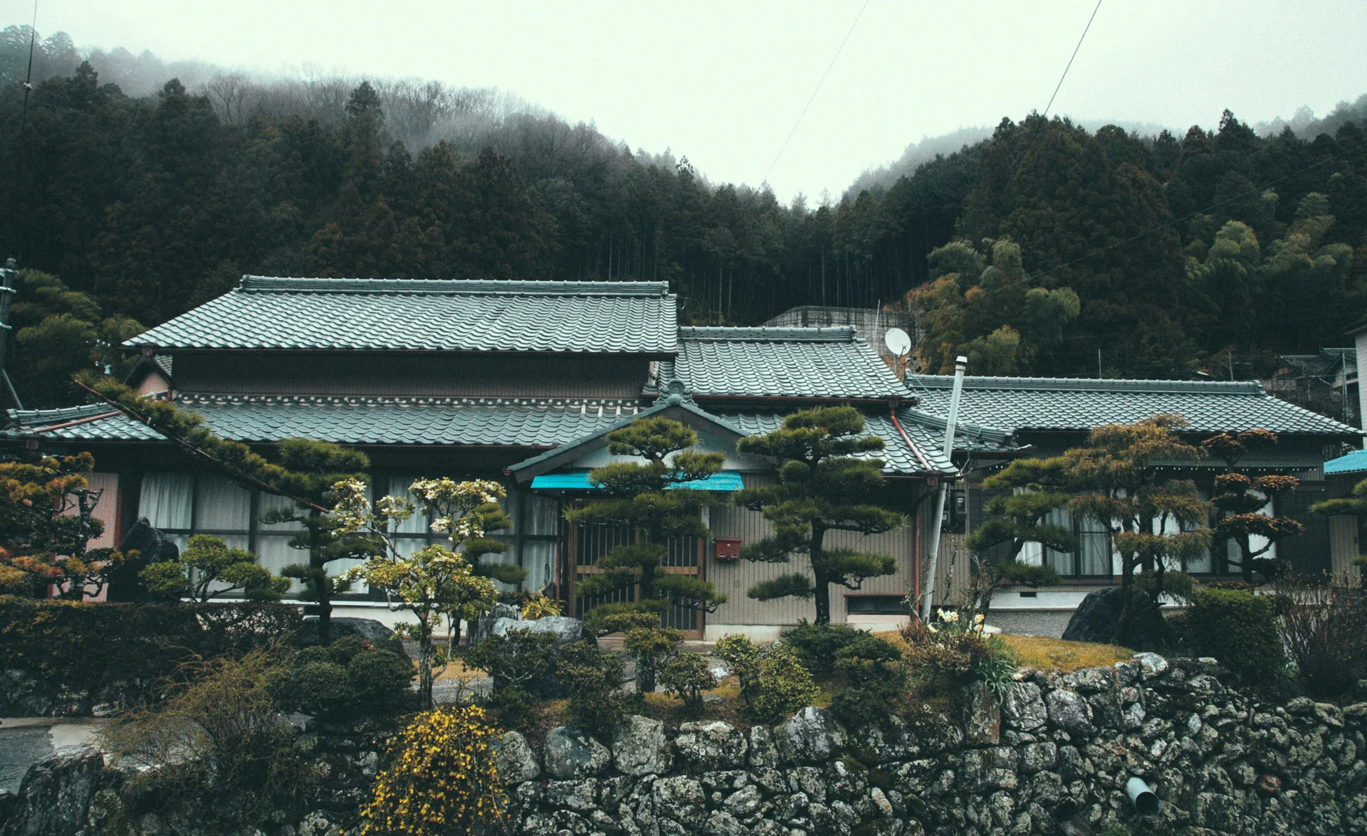 A traditional house below misty mountains
