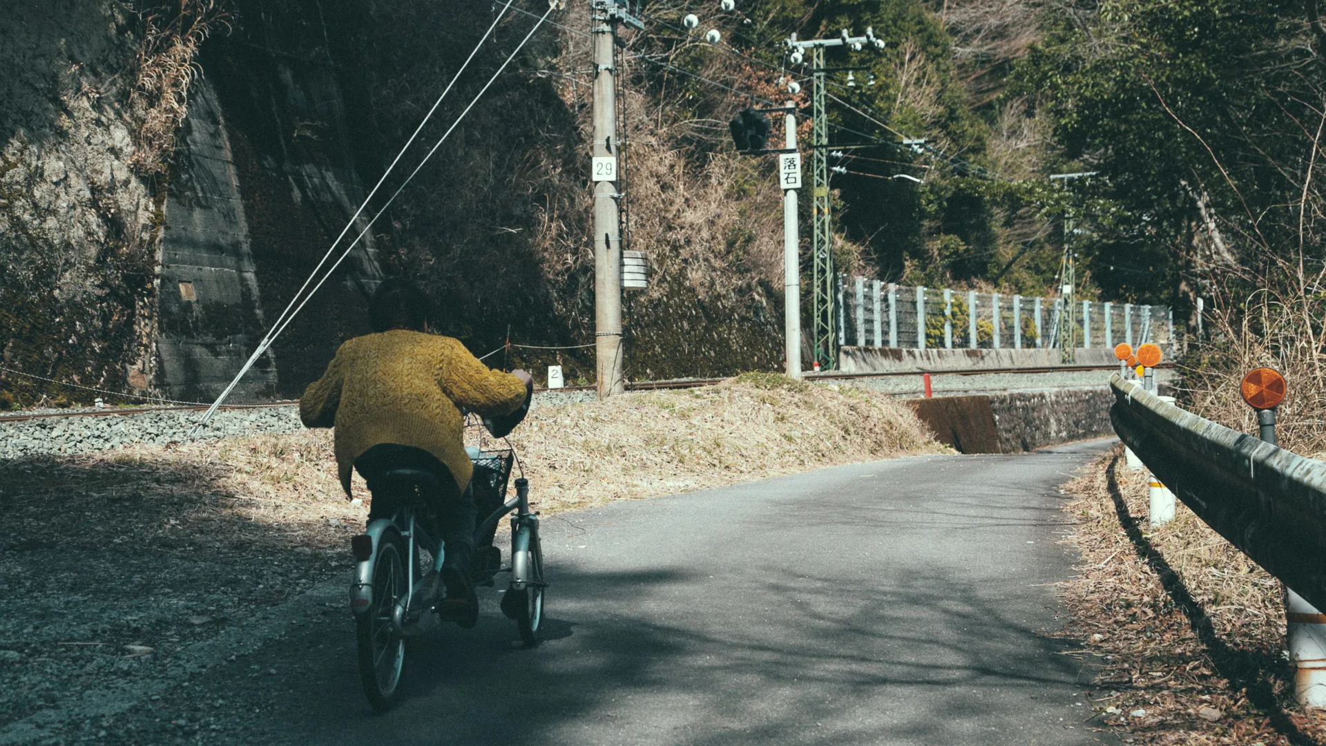 A man cycling along the road by the railway