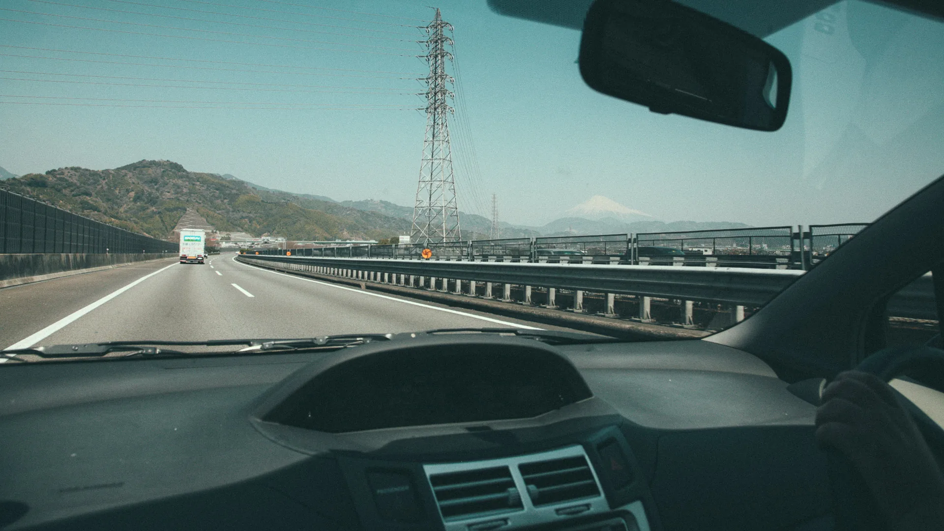 Mount Fuji appearing beyond the expressway through the windshield