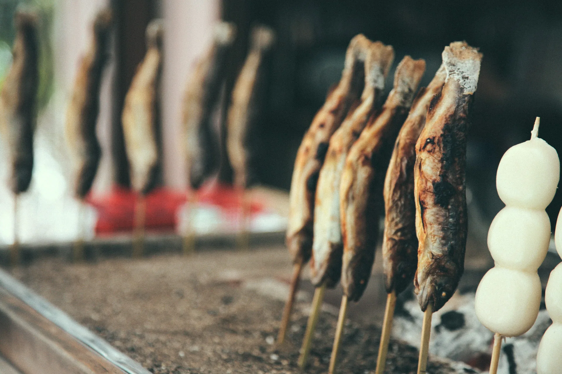 Grilled fish on skewers next to dango