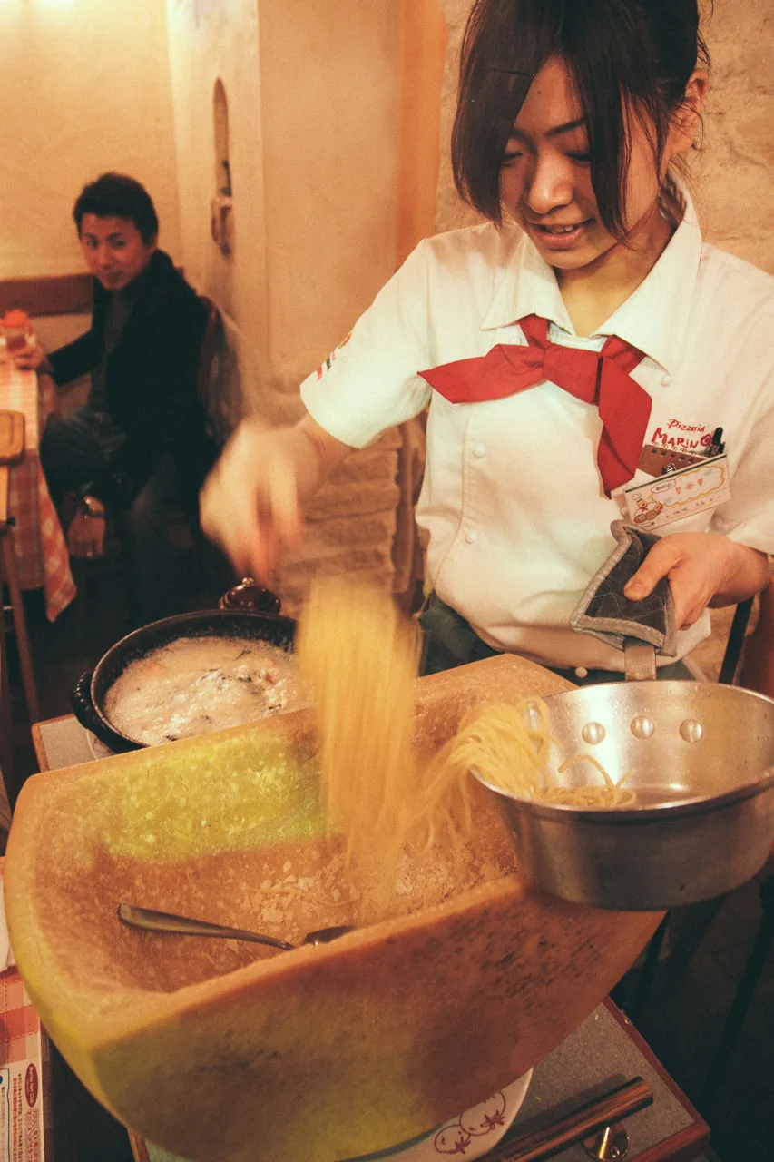 Tossing pasta inside a parmesan wheel
