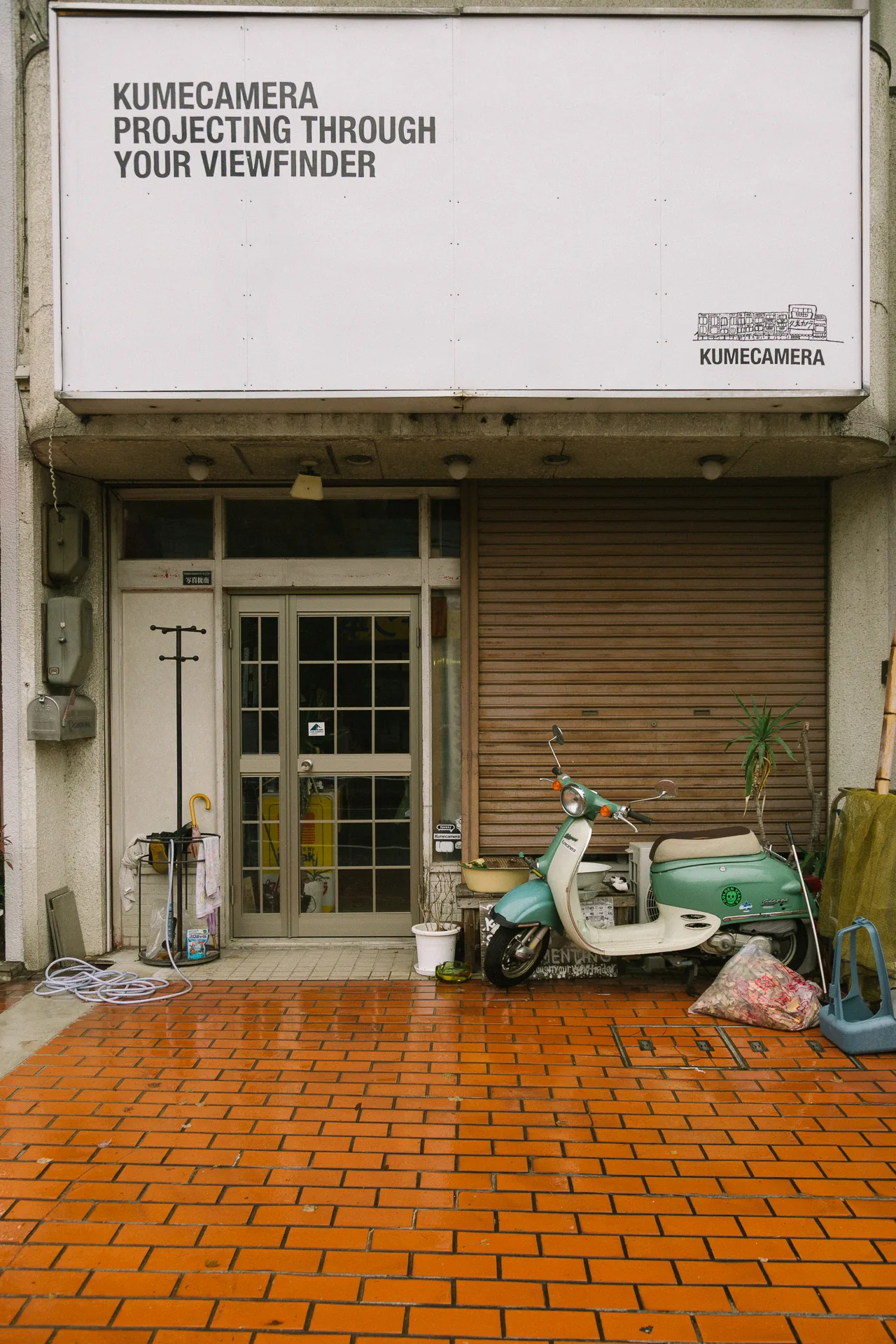 A storefront with a scooter parked on orange tiles