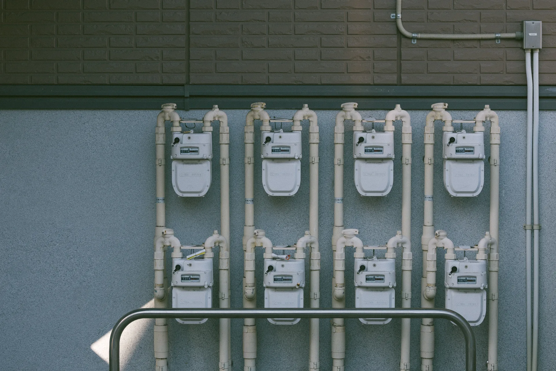 Eight gas meters on a pale blue wall