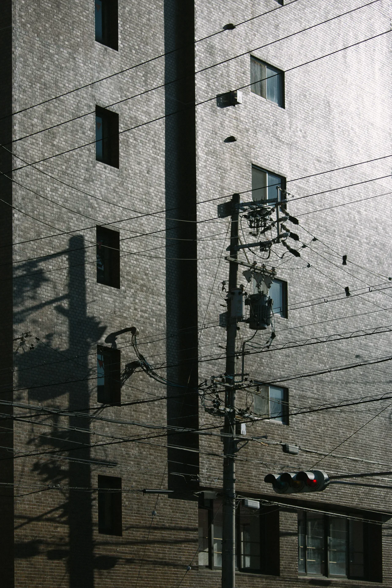 A narrow building reflected behind wires