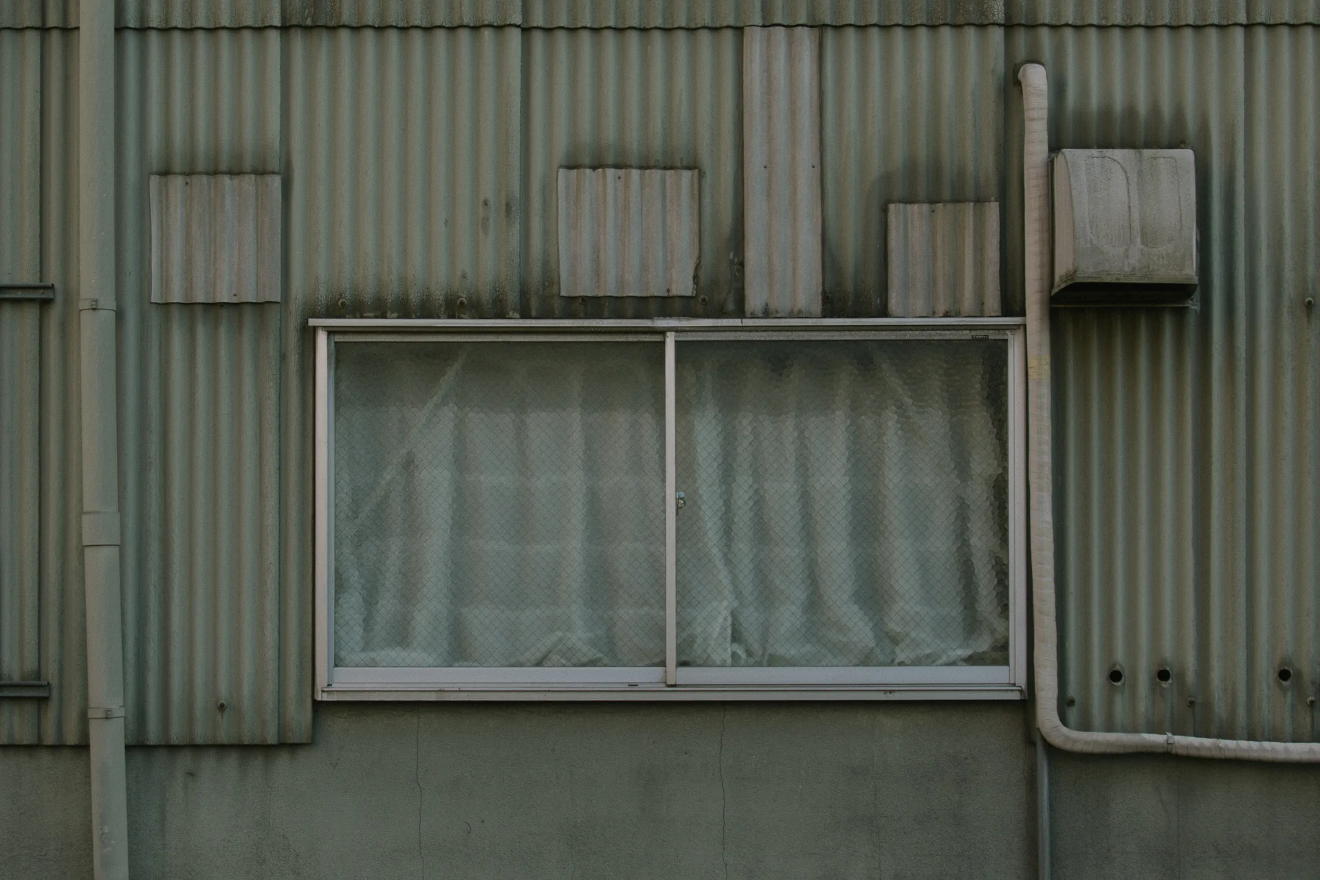 Closed curtains in a window of a corrugated wall