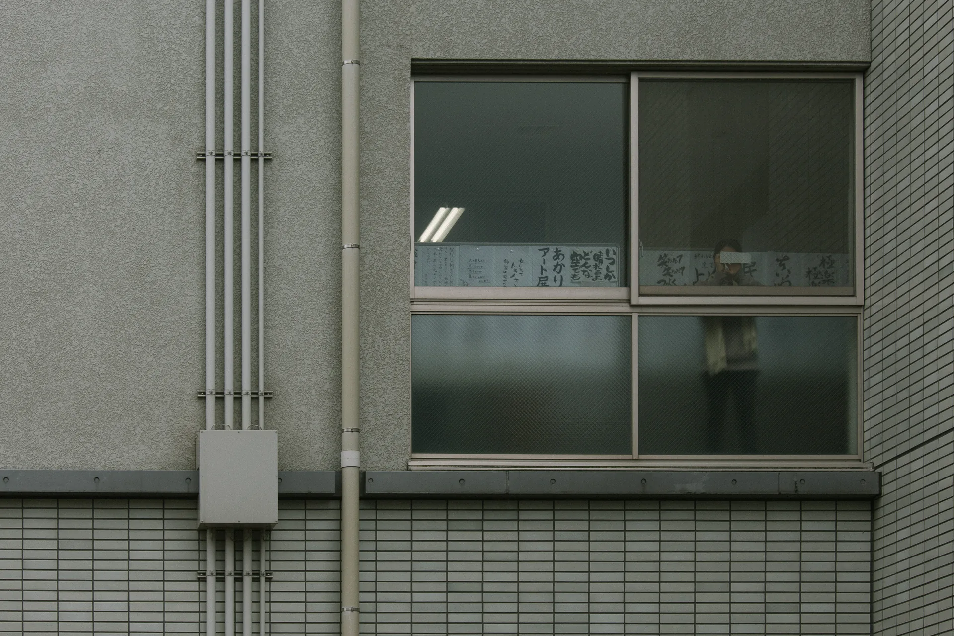 A school window and conduit on a tiled wall
