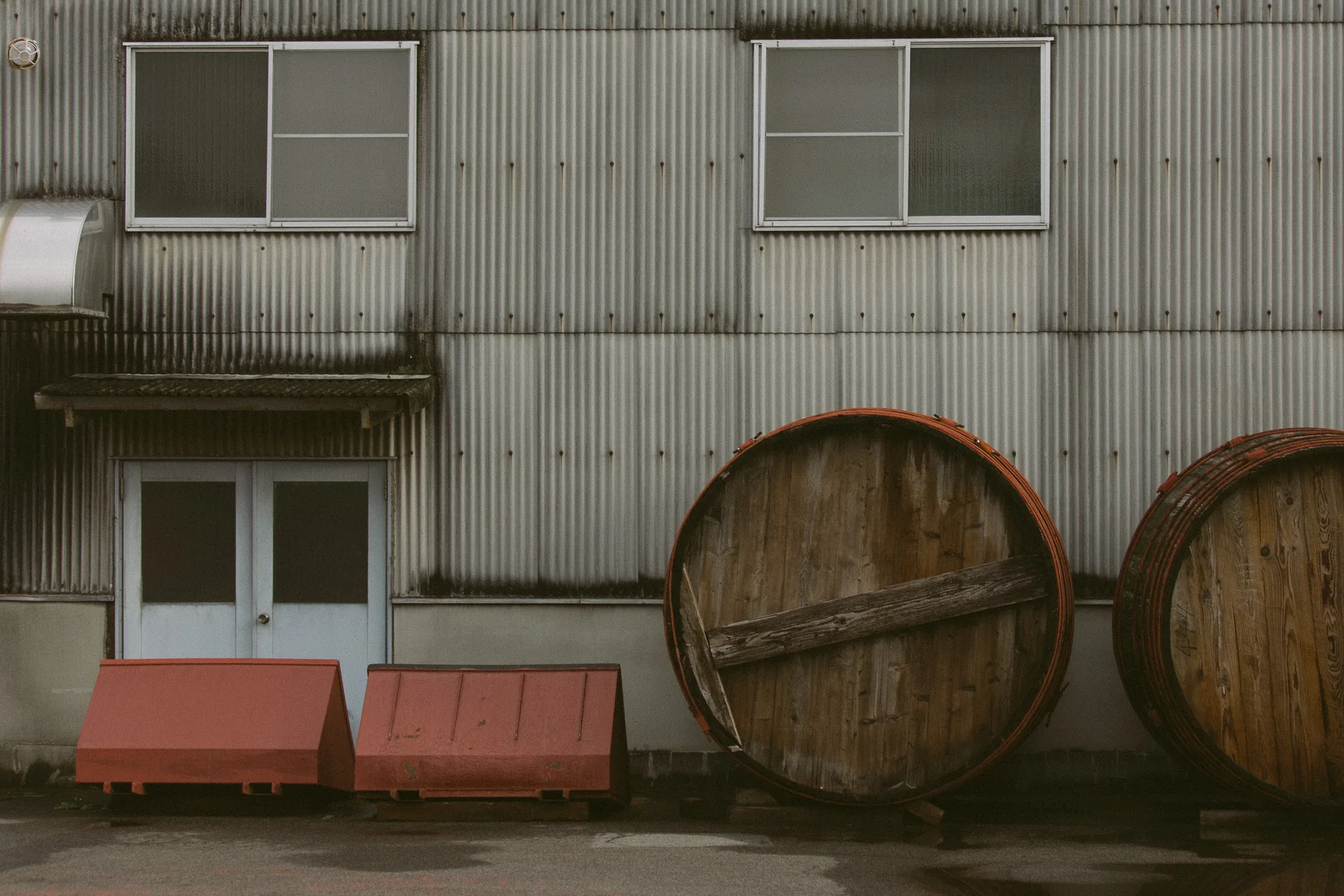 Two wooden barrels beside a corrugated building