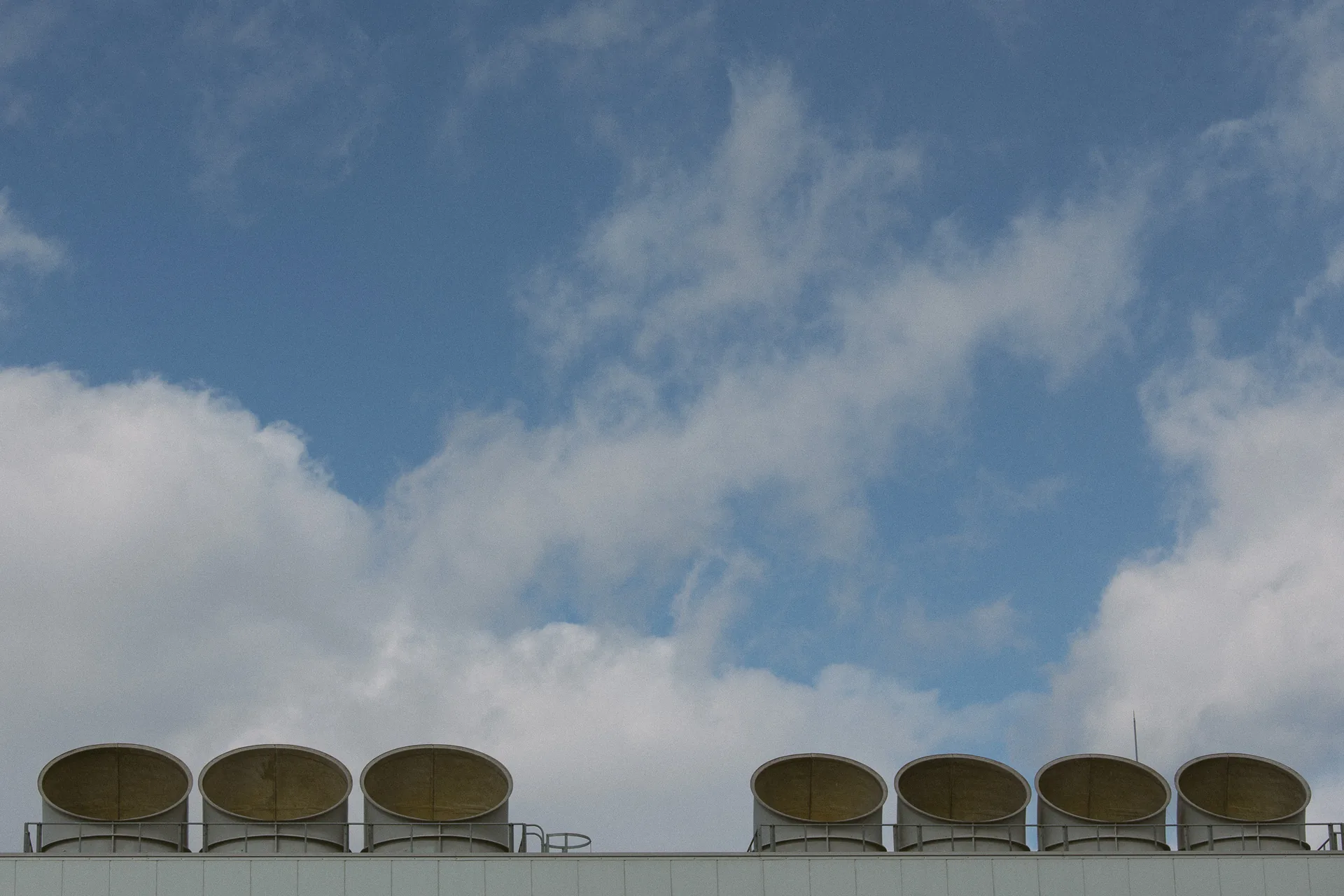 Seven rooftop vents against a blue sky