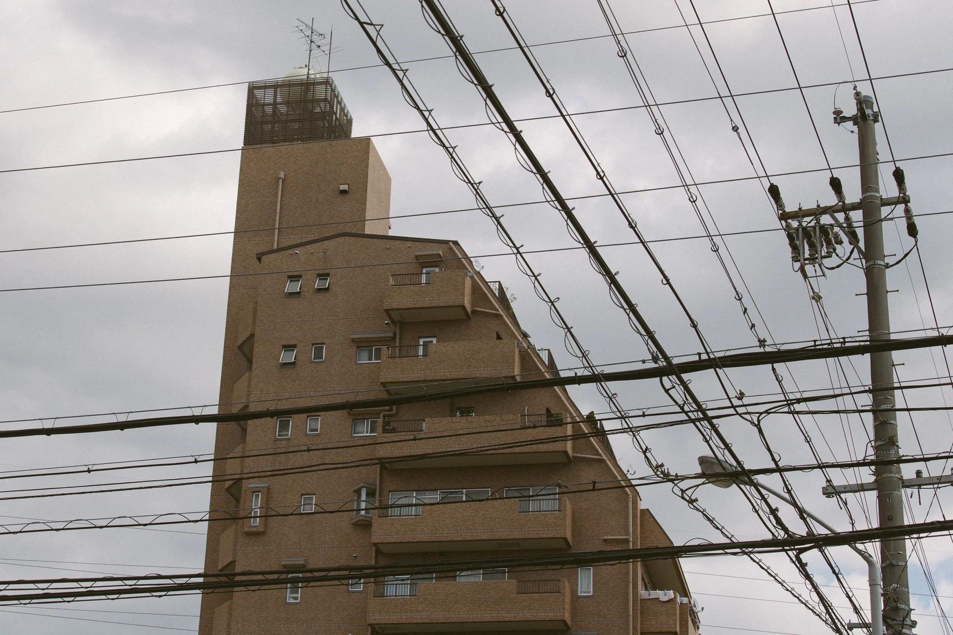 A triangular red-brown building cut by power lines