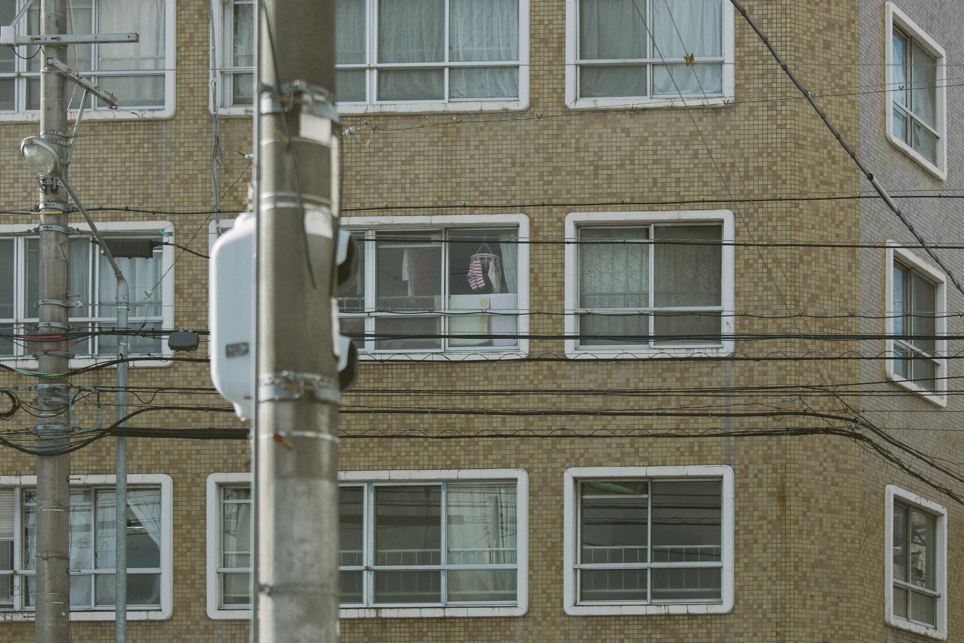 Laundry at a window behind wires and a pole