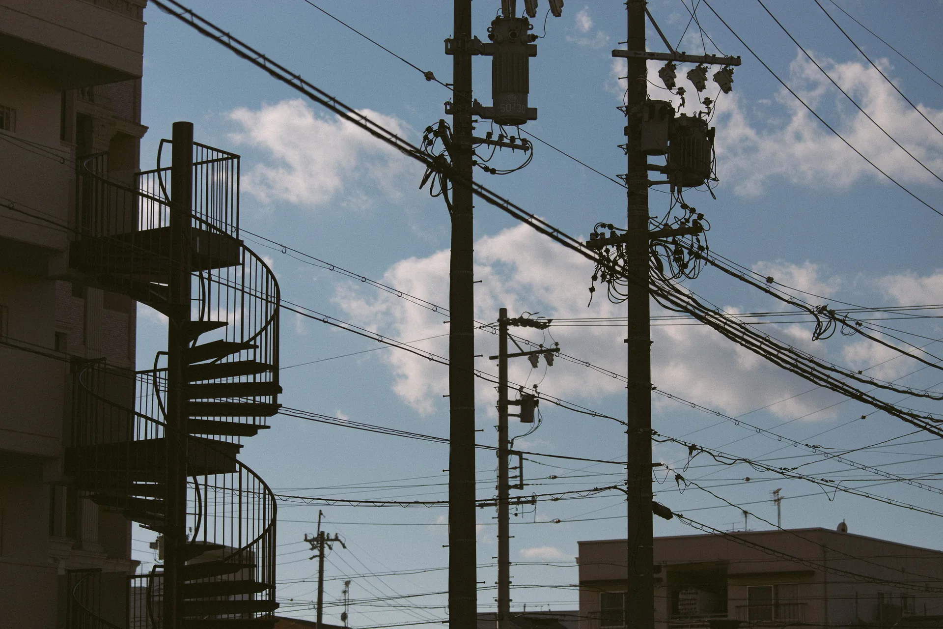 A spiral staircase among poles and wires