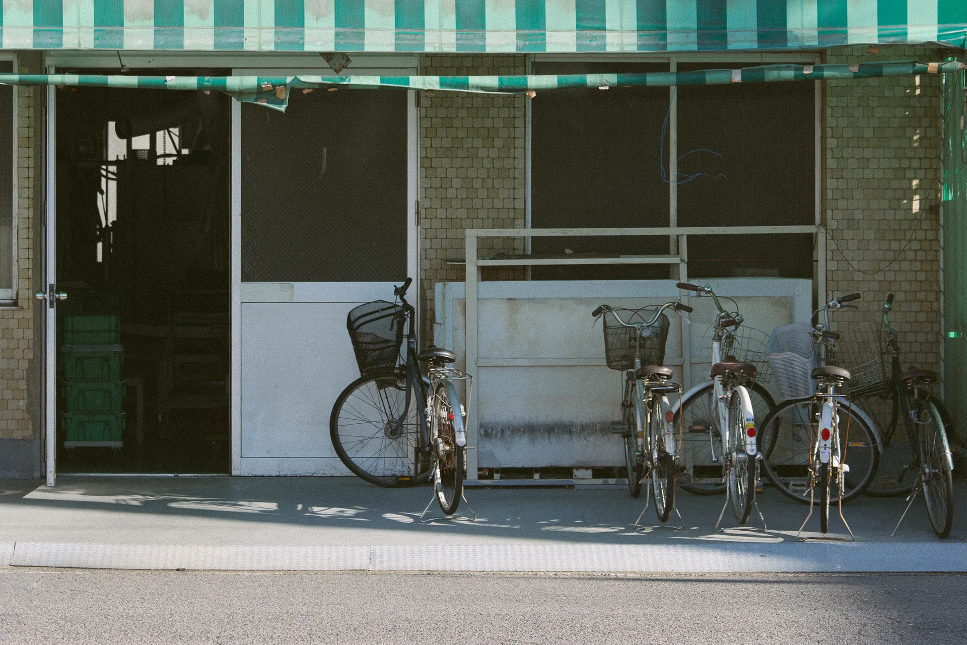 Five bicycles in front of a shop with a green awning