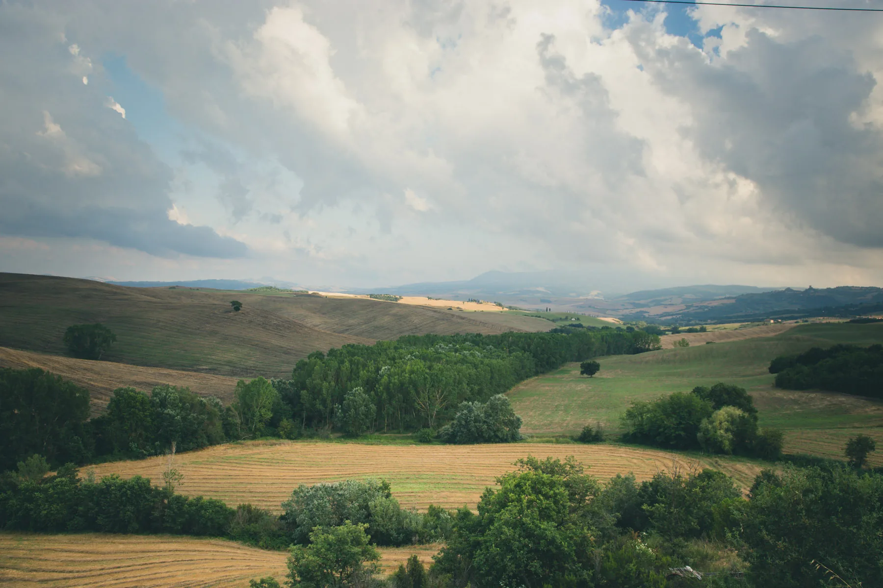 Valley of woods and fields under breaking clouds
