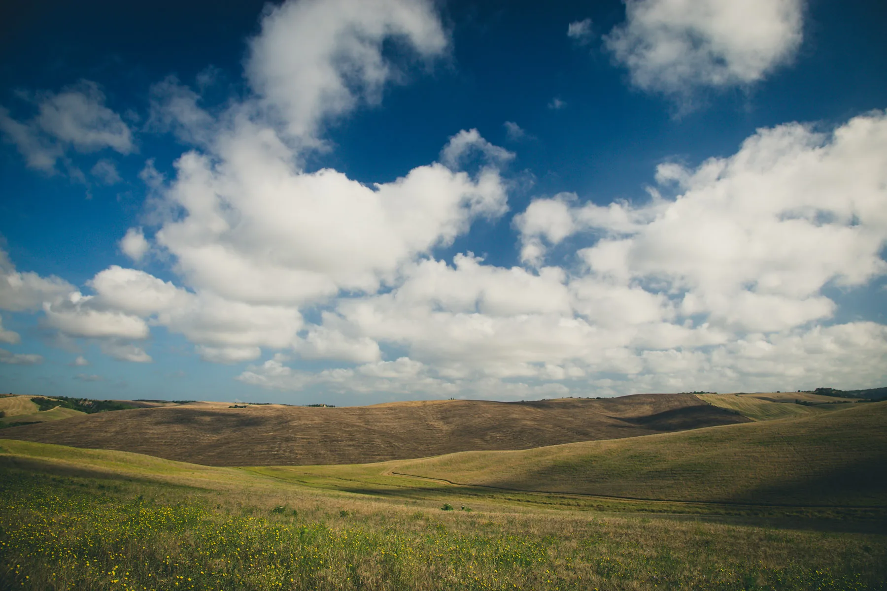 Billowing white clouds over dark rolling hills