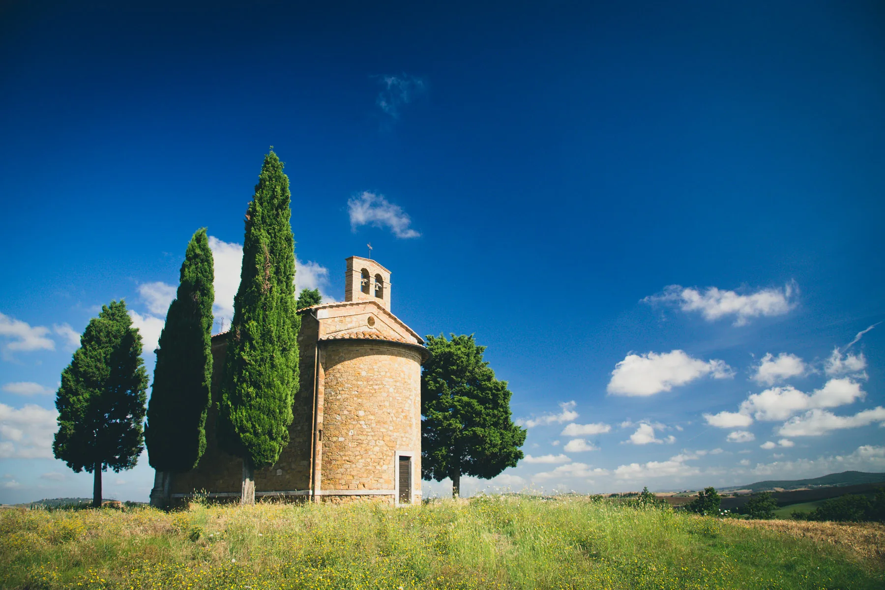 Chapel of Vitaleta flanked by tall cypresses under a blue sky