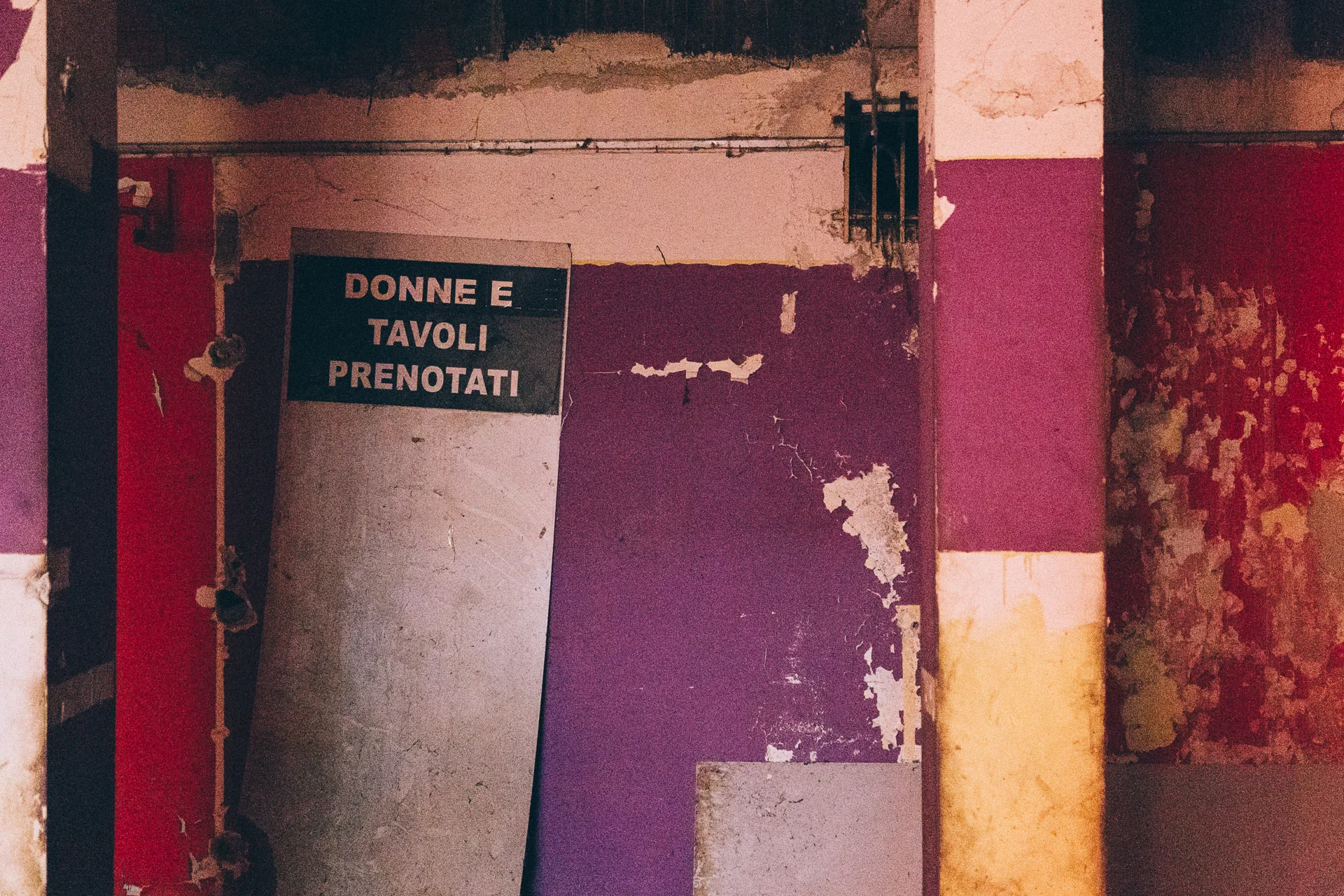 A faded reservations sign by a purple and red doorway