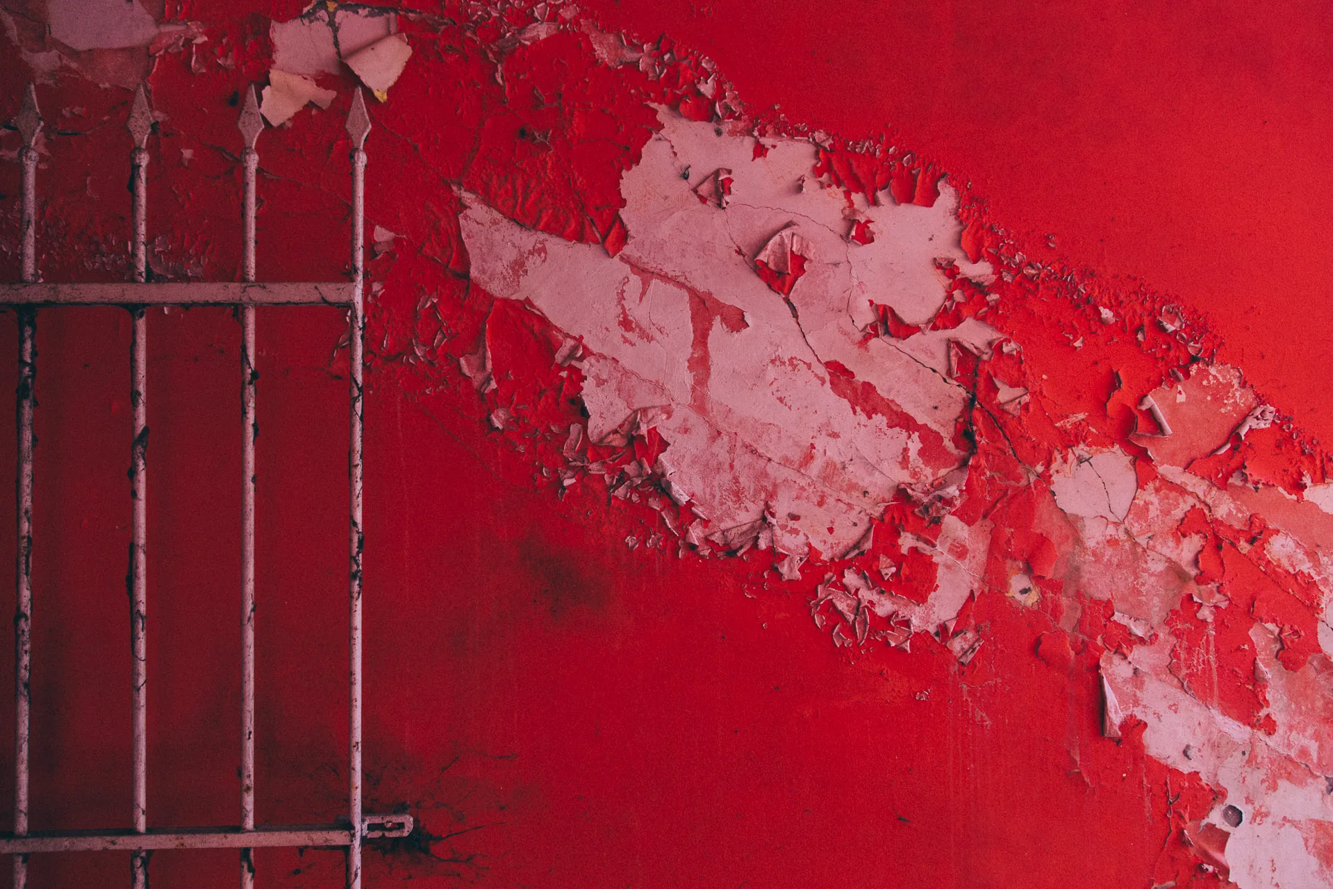 Peeling red paint beside a metal grille