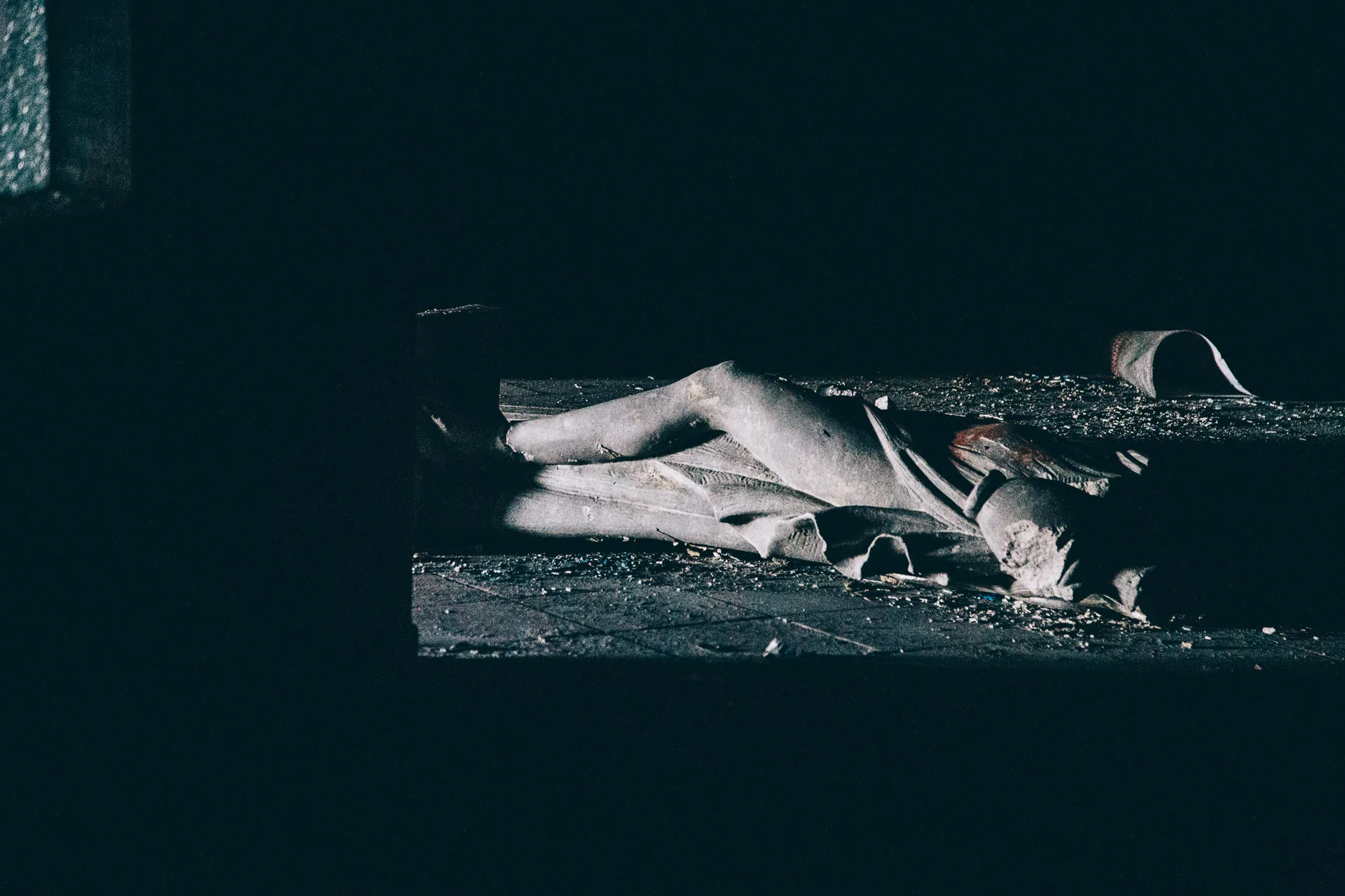 A mannequin lying in a pool of light on the floor