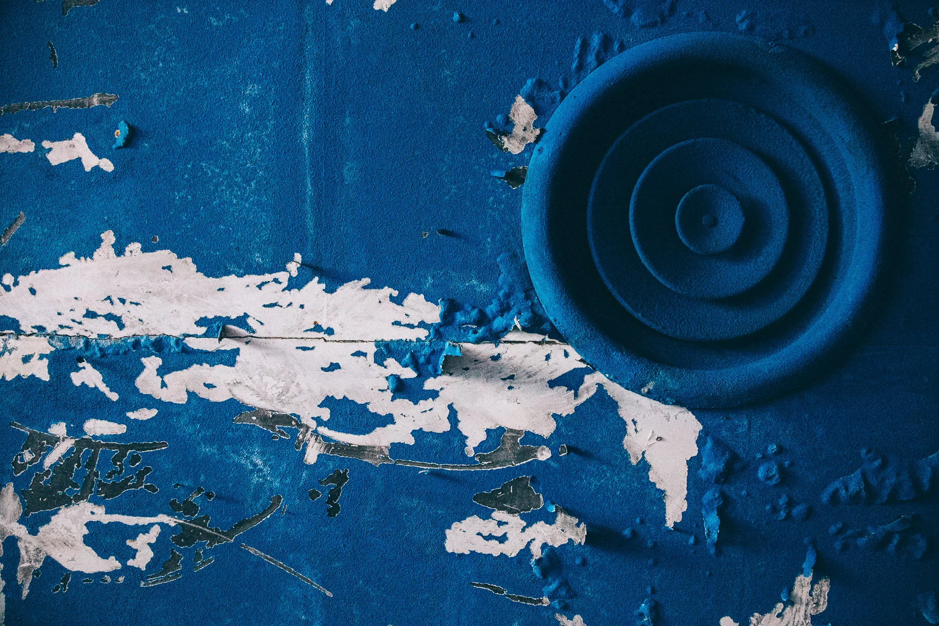 Blue paint peeling around a circular grille