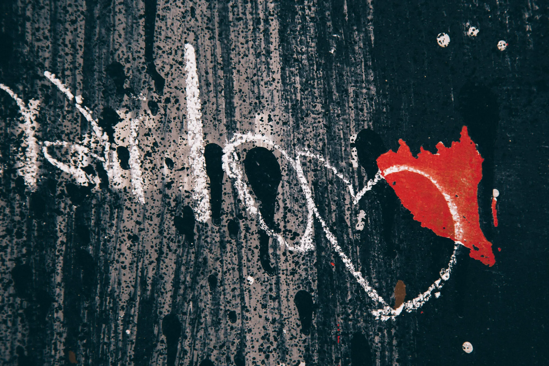 A white scrawl and a splash of red on a black wall