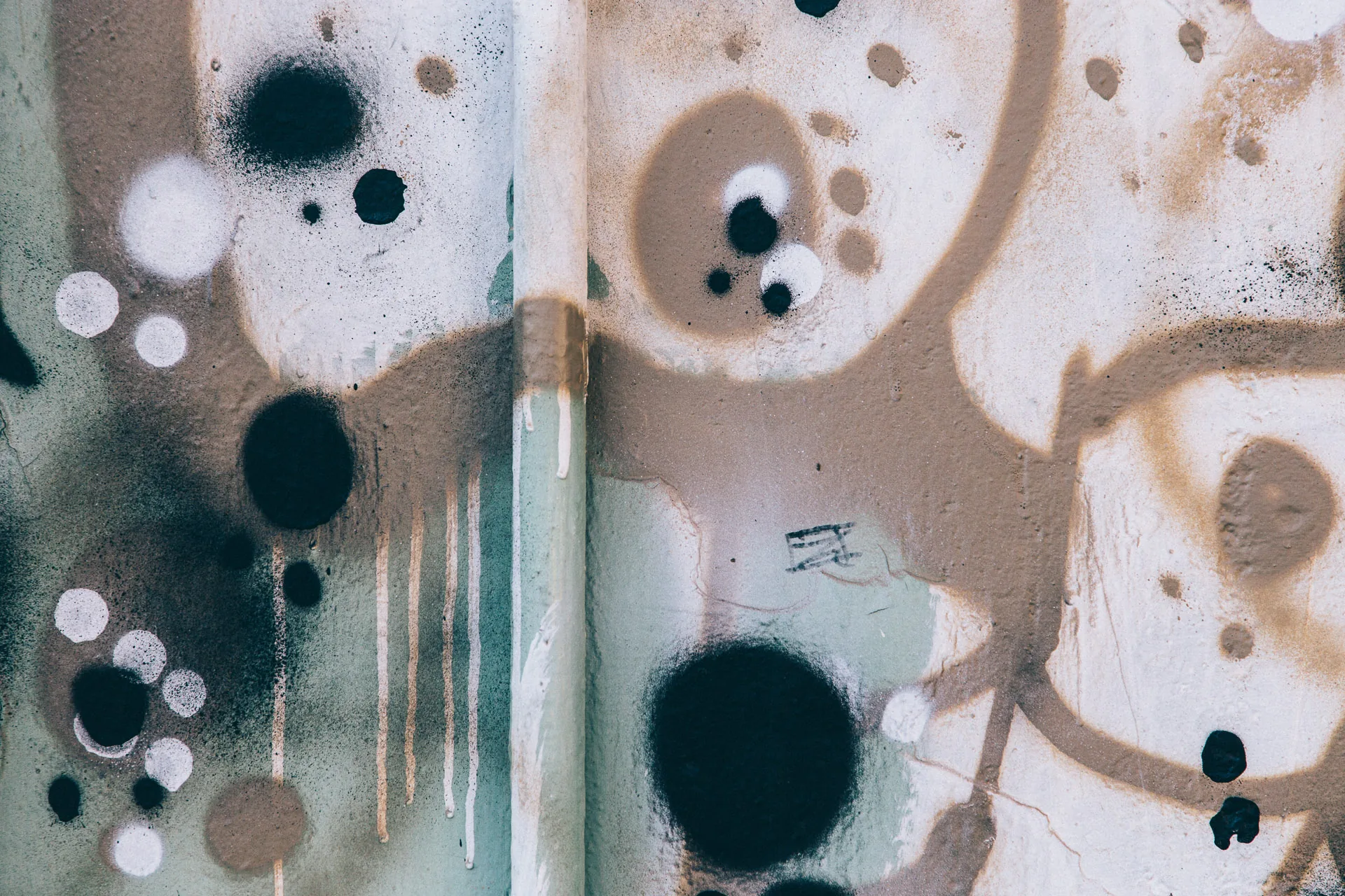 Black and grey spray-paint circles on a pale wall
