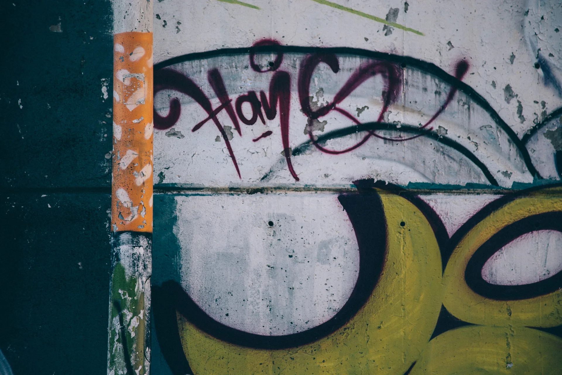 Black and yellow graffiti letters on a concrete wall