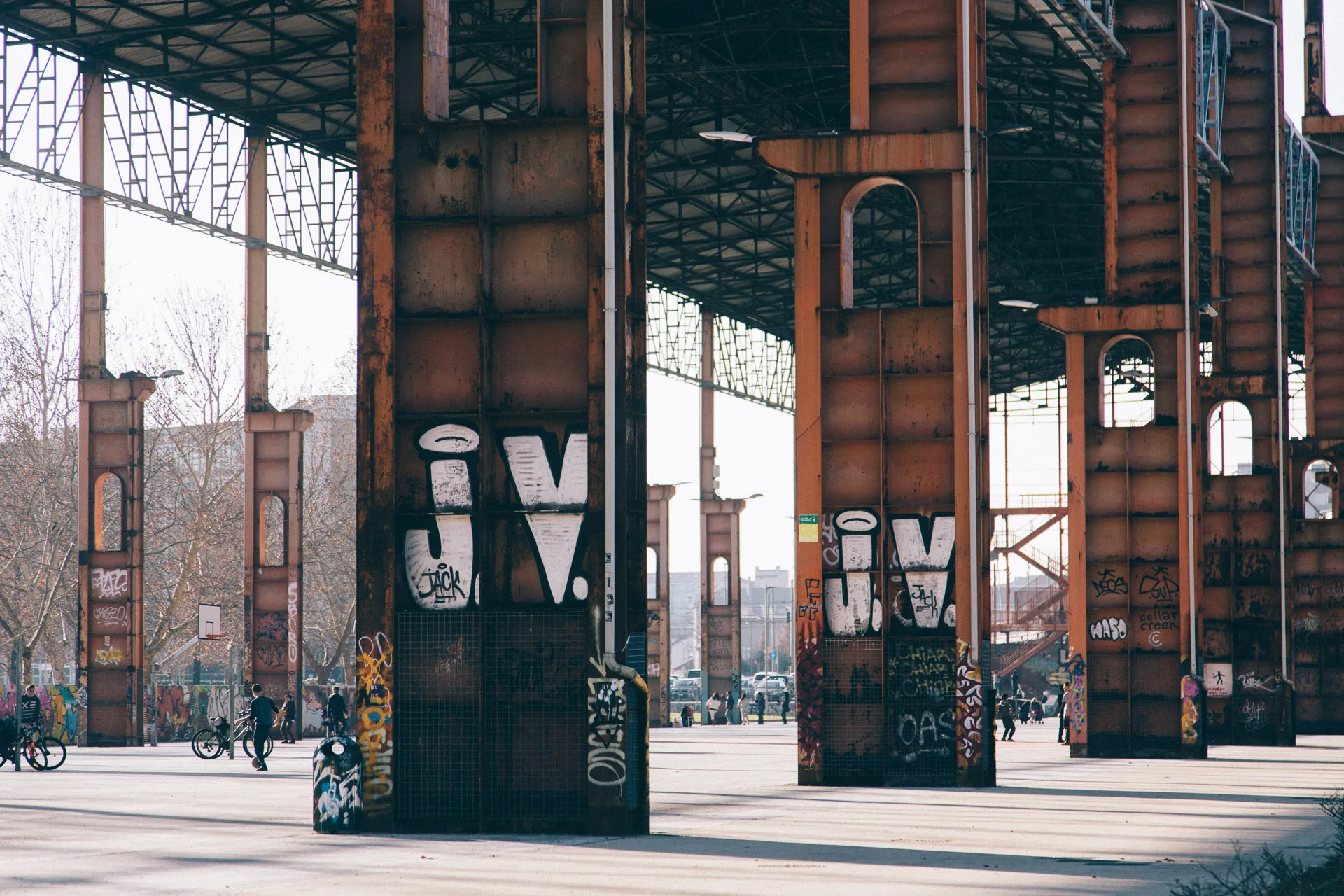 Rusted pillars marked with graffiti in a sunlit park