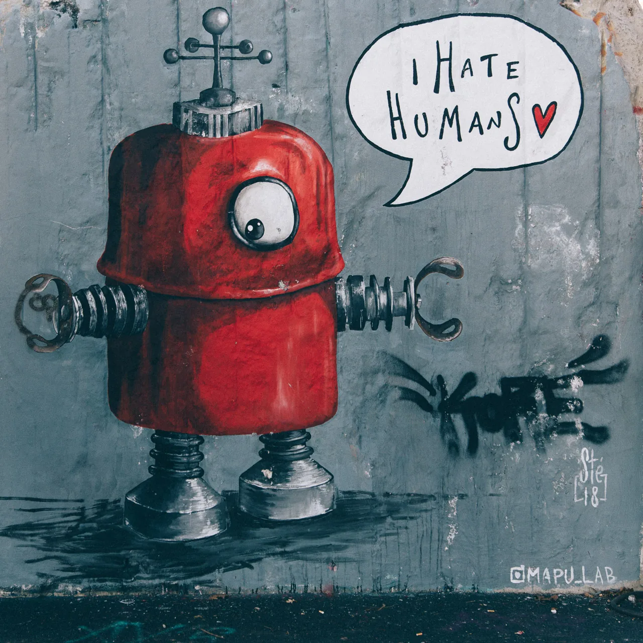 A painted red robot with a speech bubble on a wall